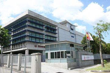 Wisma QL, QL Resources’ head office, with the company’s name on the building and at the gate.