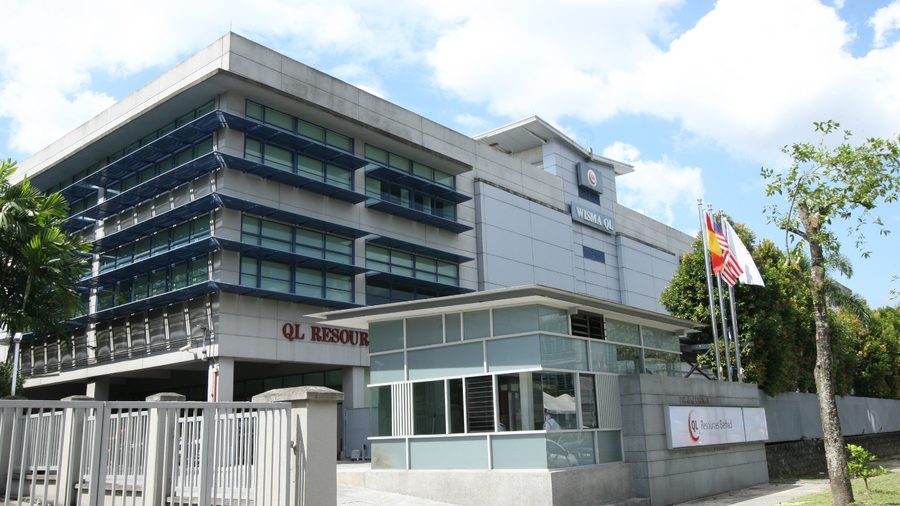 Wisma QL, QL Resources’ head office, with the company’s name on the building and at the gate.